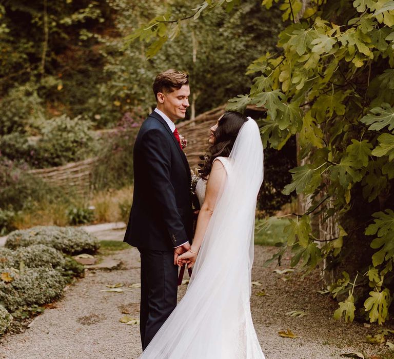 Bride in church length red ombre veil laughing with groom wearing deep blue grooms blazer, grey waistcoat and red tie at The Orangery Maidstone wedding venue 