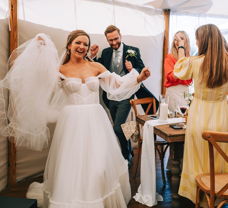 Bride in tulle bridal gown enters the marquee wedding breakfast with the groom to the cricket theme song 