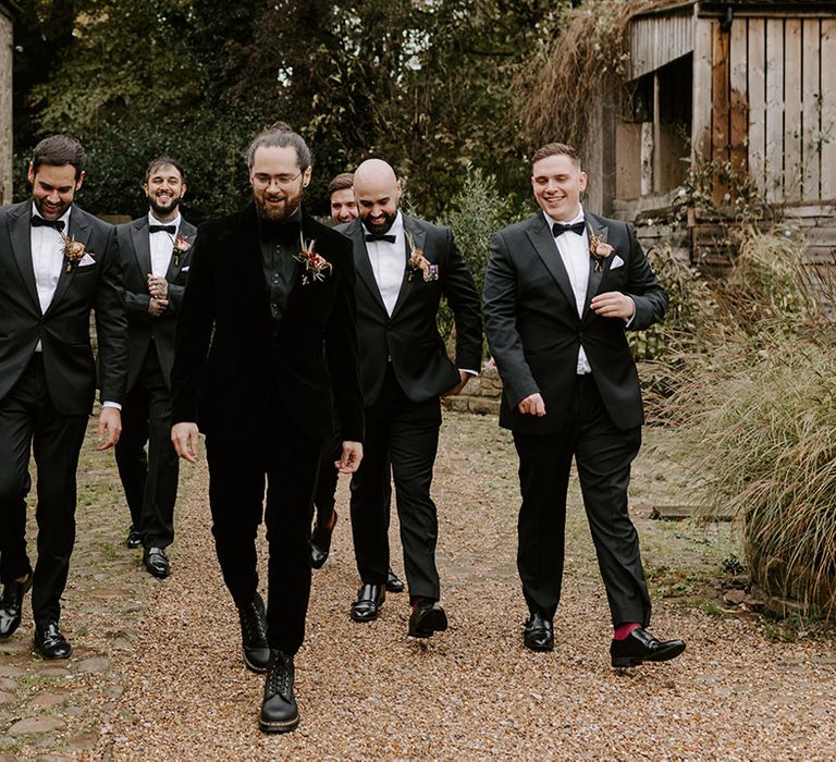 Groomsmen in matching black tie for the wedding day with the groom in a black velvet suit 