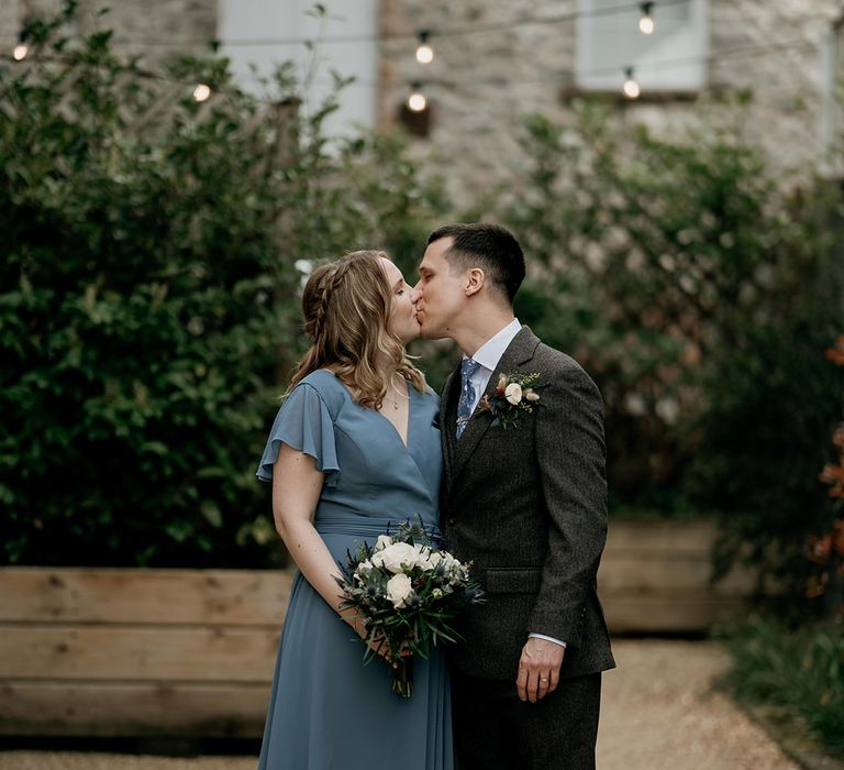 The bridesmaid in a blue dress kisses her groomsman at the wedding 