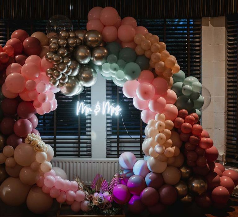 Neon wedding sign in large wedding balloon arch with pampas grass wedding decor and garden rose arrangements 