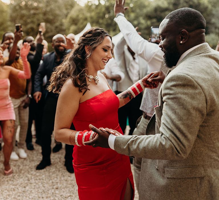 Bride in bold strapless red wedding reception dress with the groom dancing together 