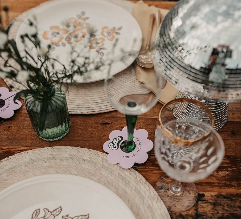 Charger plates, painted crockery, green coloured glassware and disco ball decor 