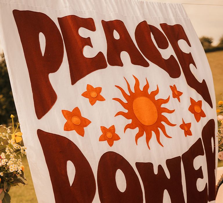 Peace and power wedding banner sign for outdoor wedding ceremony at free-spirited boho wedding 