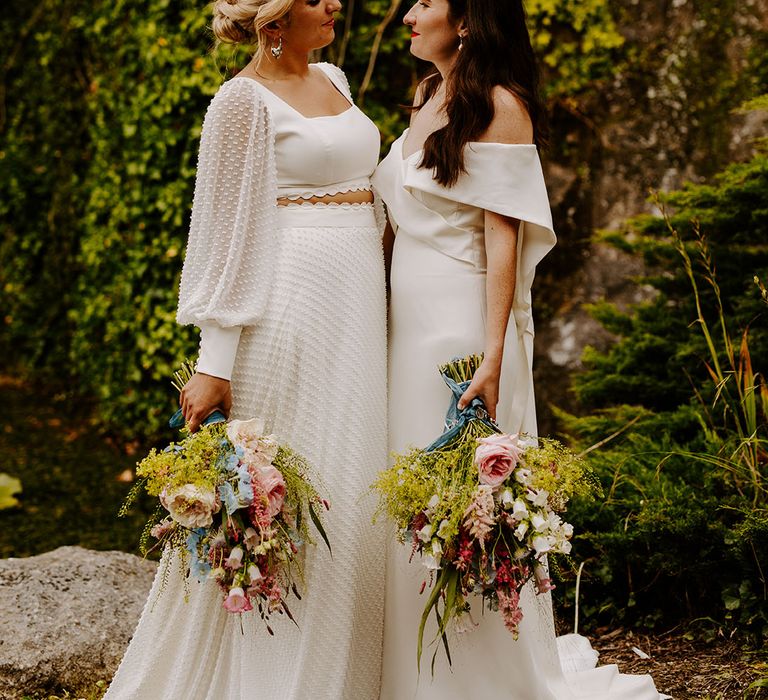 Bride in textured spotted long sleeve top and skirt separates with bride in off the shoulder gown and pearl hair piece at same sex lesbian wedding 