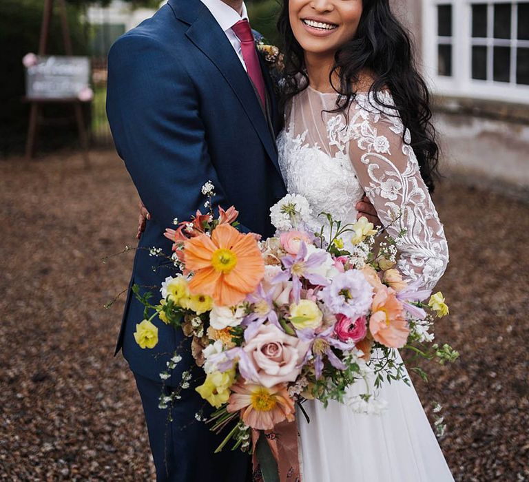 Bride holding colourful spring wedding flowers in a stunning bouquet with Icelandic poppies and roses 