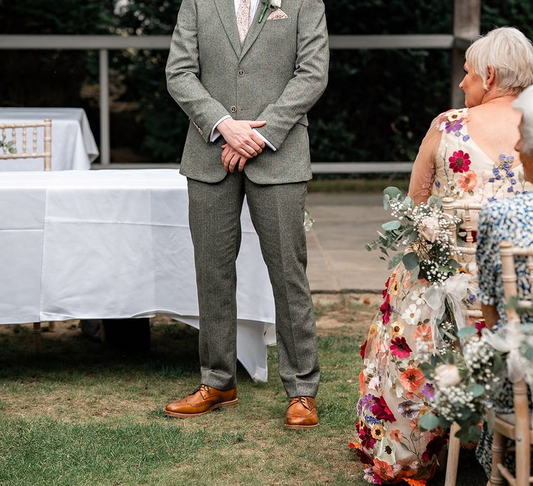 Groom in grey wedding suit waits for the bride at the wedding ceremony 