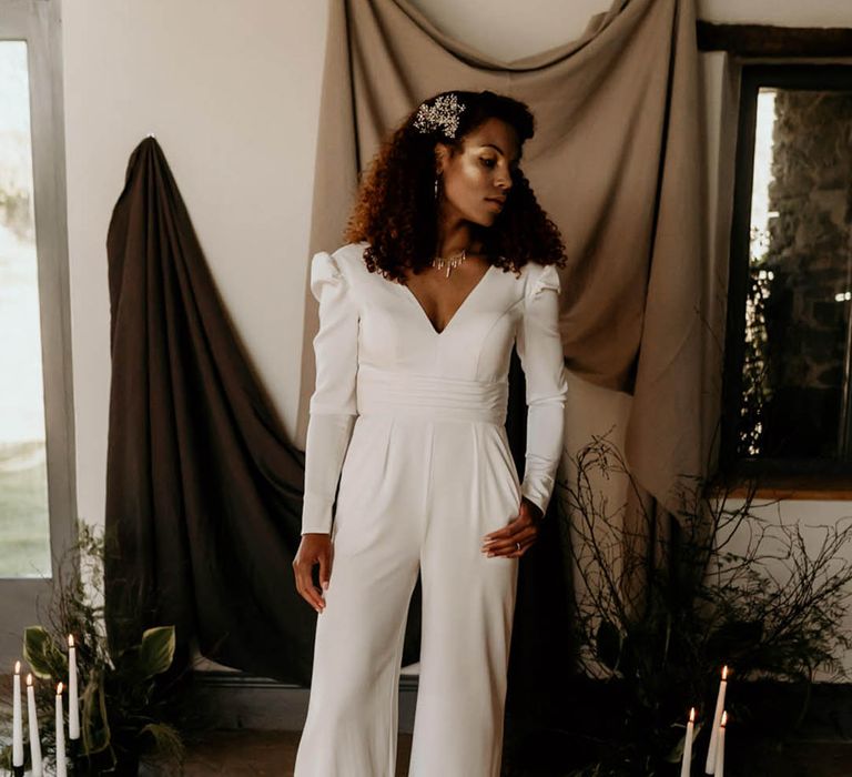 Bride wears double breasted white suit complete with wide leg trousers and neutral heels 