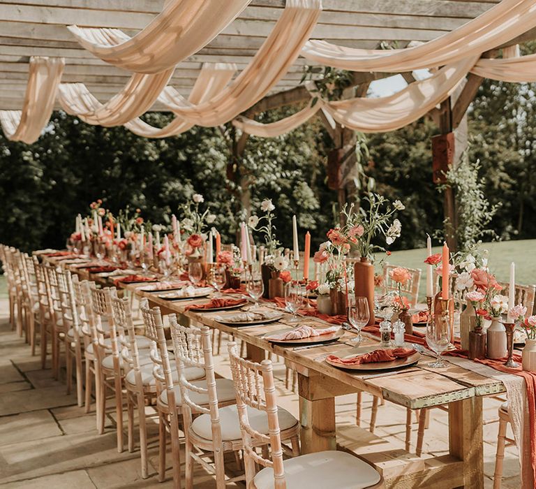 Boho burnt orange wedding theme for outdoor wedding tablescape with drapery and fabrics 