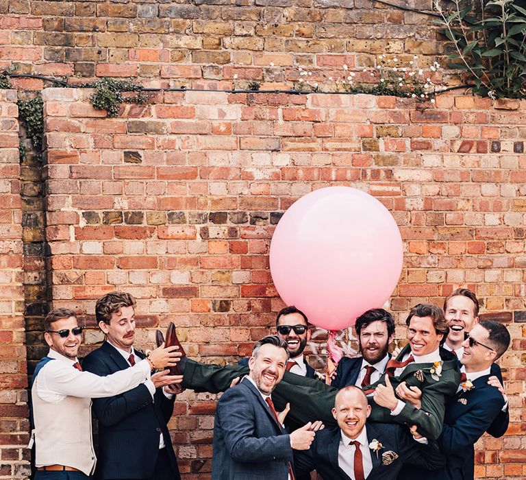 The groom and groomsmen pose for funny group photo