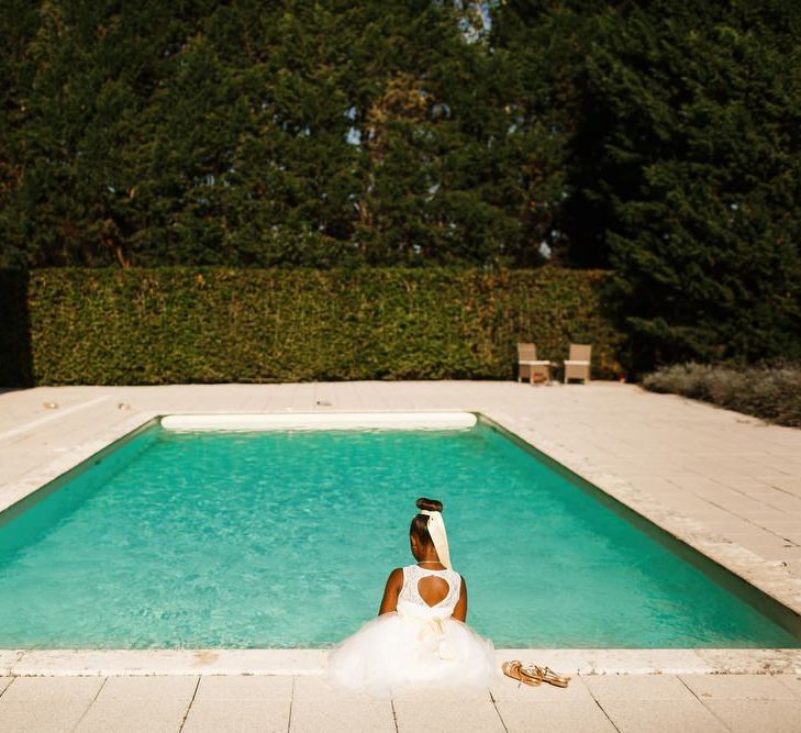 Gorgeous flower girl dips her toes in the pool on hot wedding day