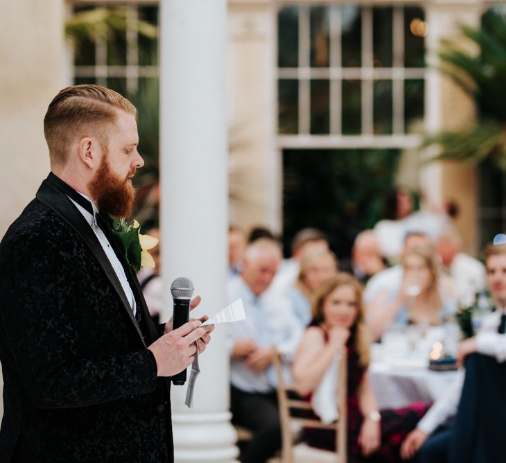 Groom in black tuxedo giving a wedding speech