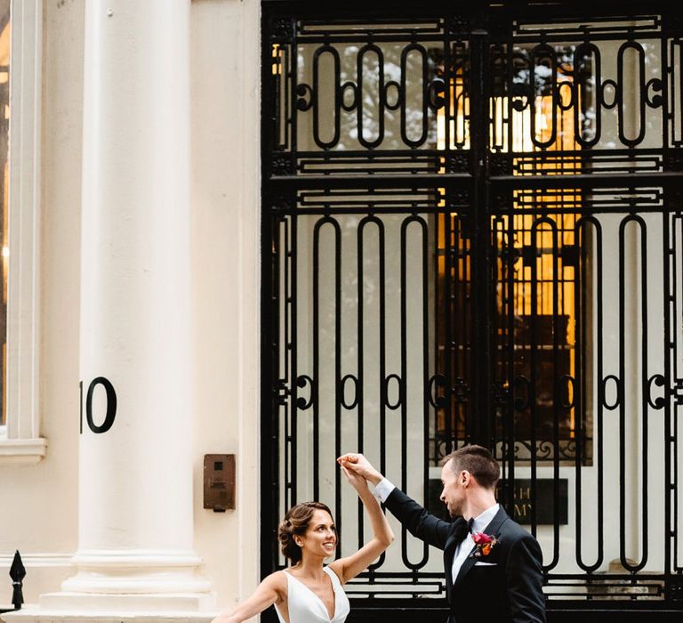 Bride and groom twirling in front of their wedding venue Carlton House Terrace