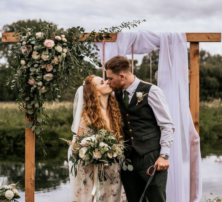 Bride & groom with their dog under floral arch 