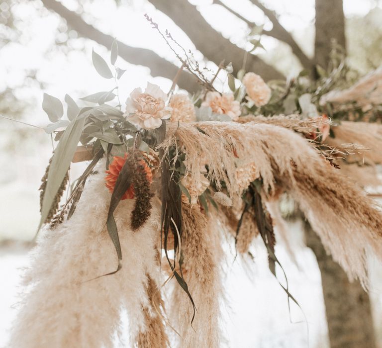 Pampas grass with white and orange flowers and green leaf foliage 