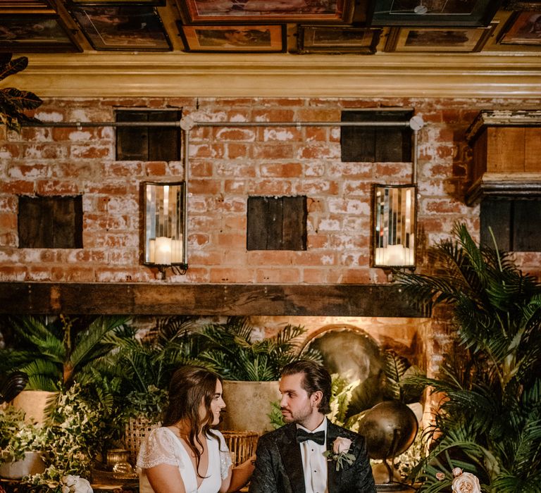 Bride and groom photography with rustic background with exotic leaves, cosy candles and red brick wall 