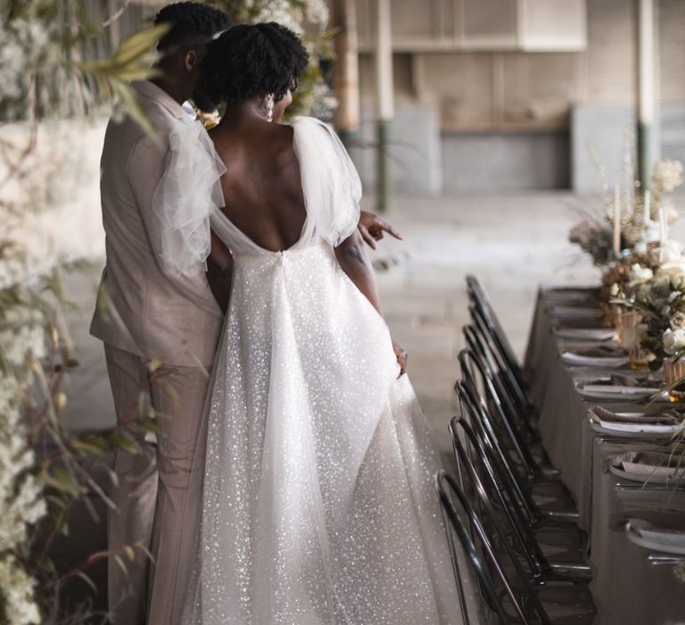 Bride in sparkly wedding dress looking at the industrial wedding reception decor 