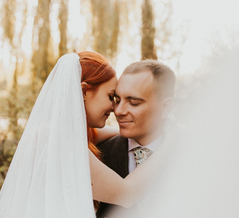 Close up photo of newly married couple hugging and smiling bride wears veil with red hair 