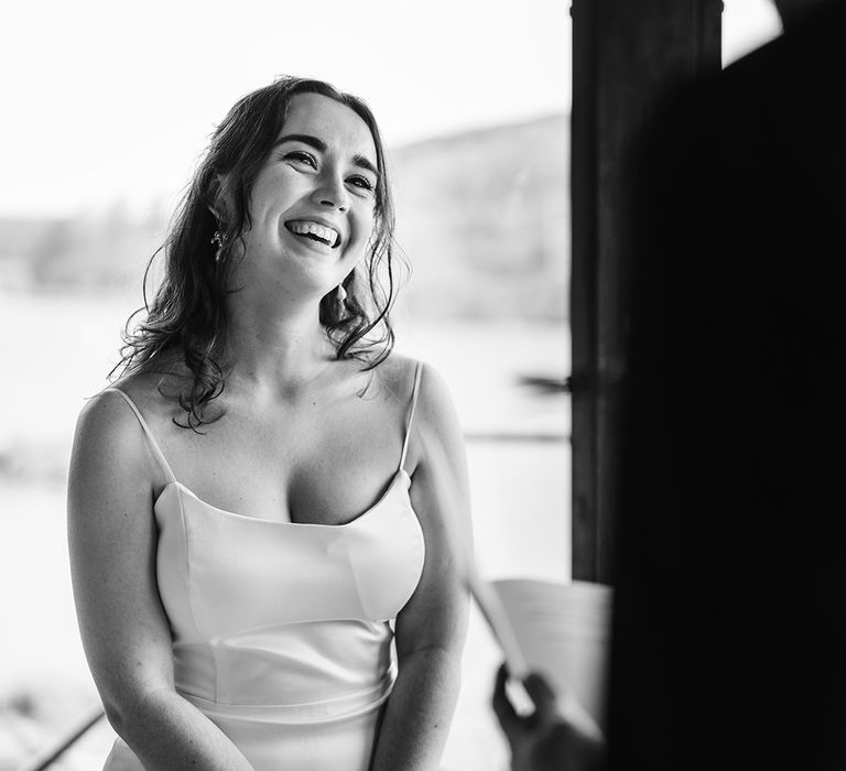 The bride smiling as the groom reads his vows