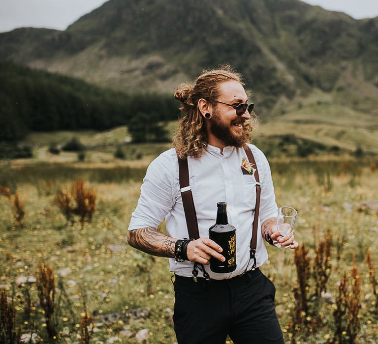 Groom celebrates with a beer after wedding ceremony outdoors