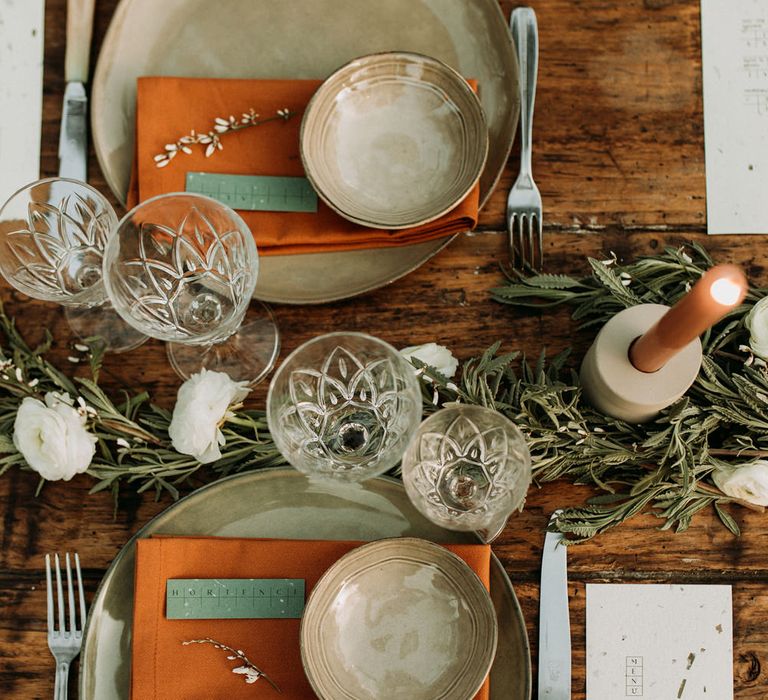 Birdseye view of table decor with green tableware and orange linen