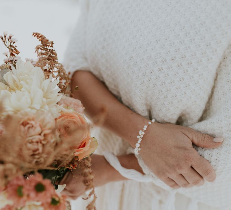 Bride in a cream waffle shawl wearing a delicate bracelet by Nila Creazioni