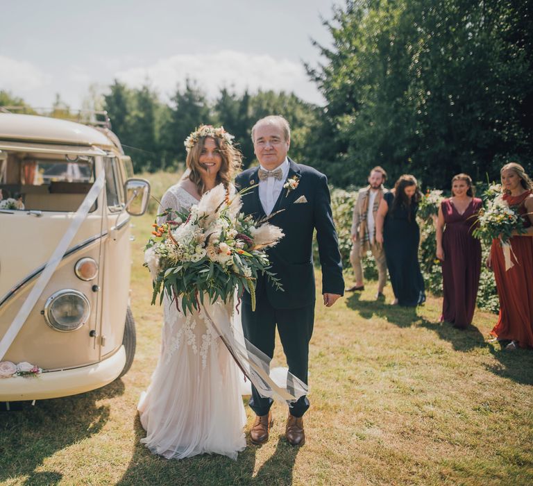 Bride walks from vintage VW camper van with father on the day of her wedding