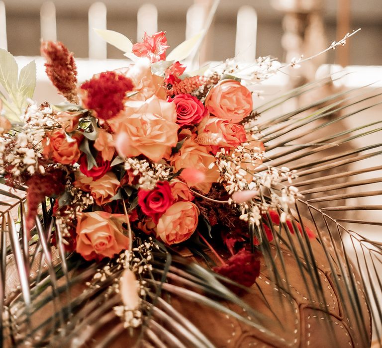 Orange and red rose and dried grass floral arrangement 