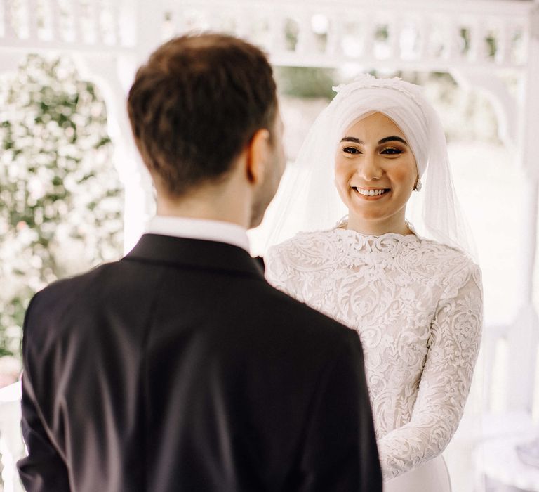 Smiling bride with beaded earrings and high neck and long sleeve 3D lace wedding dress 