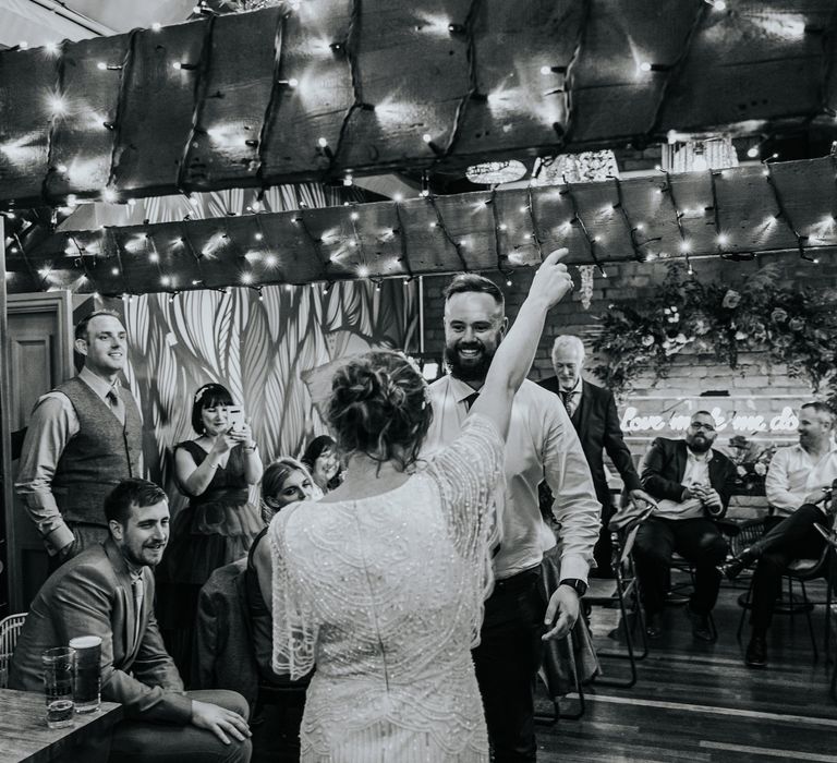 Bride & groom dance with one another at wedding reception in black & white image