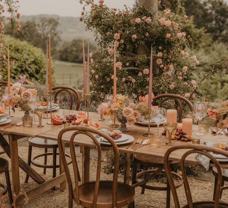 Outdoor summer wedding table decor with taper candles, centrepiece flowers and elegant tableware 