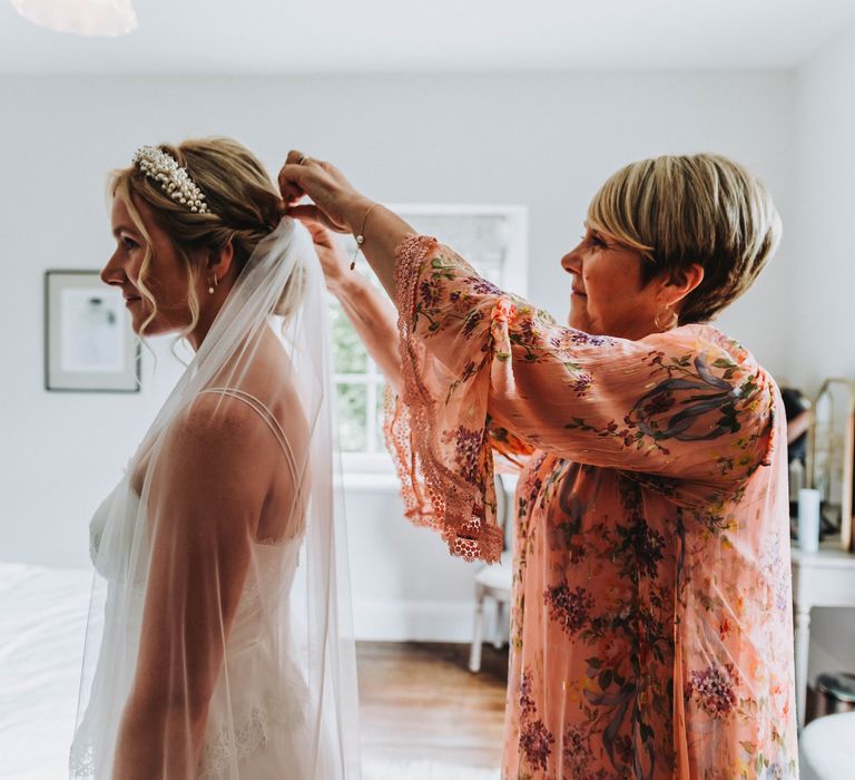 Wedding guest applies veil to brides hair on her wedding day