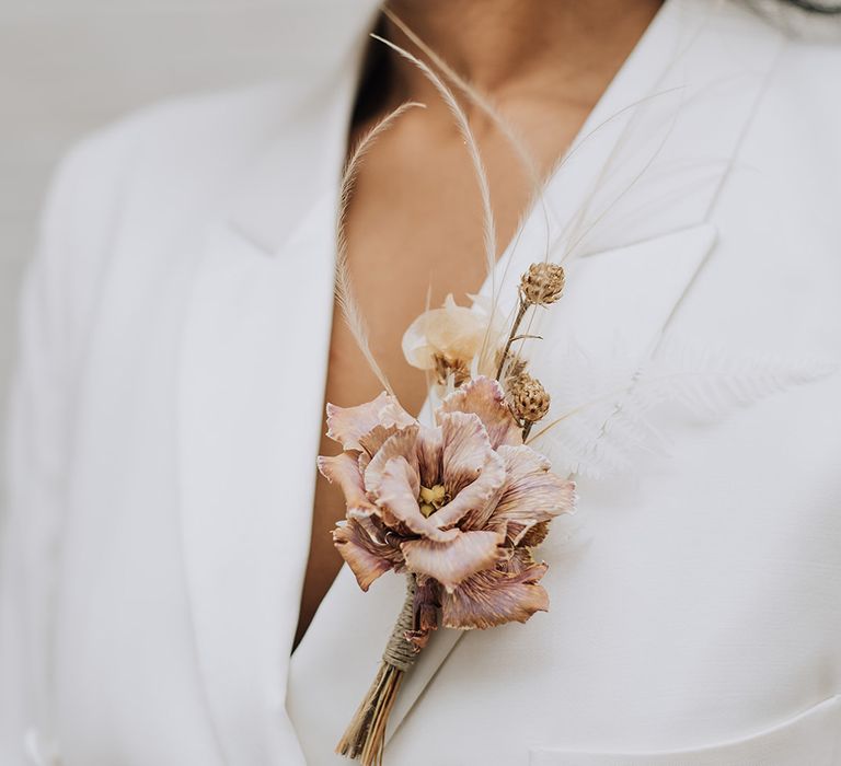 Bride in a white suit with a sucky pink gladioli buttonhole flower 