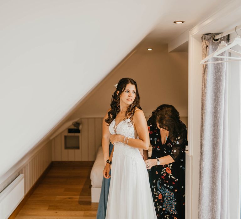 Bride has her wedding dress done up on the morning of her wedding by guest