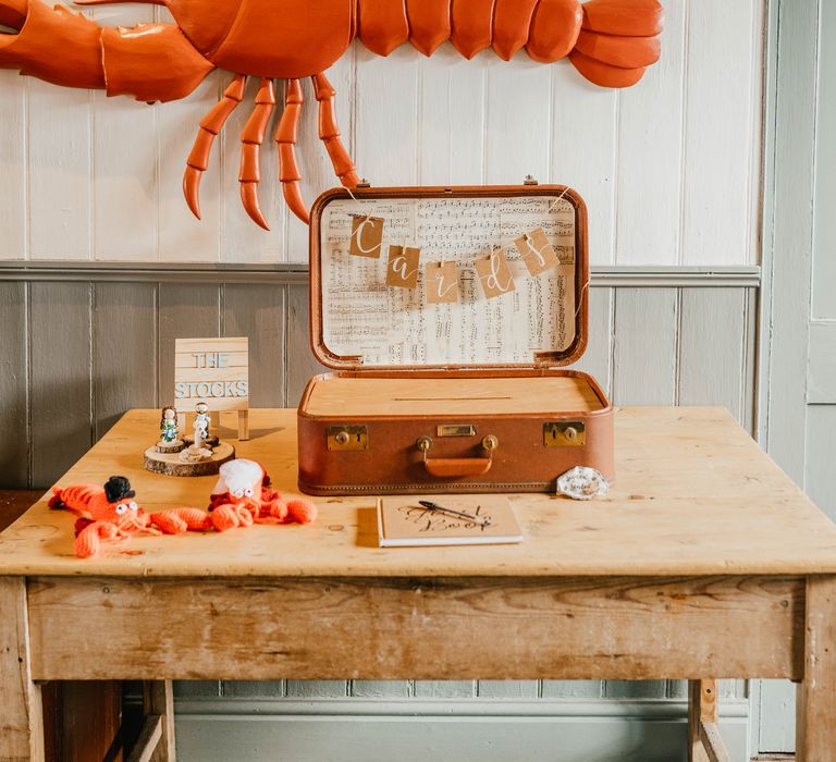 Handmade crochet lobsters in brown vintage suitcase with large plastic lobster above