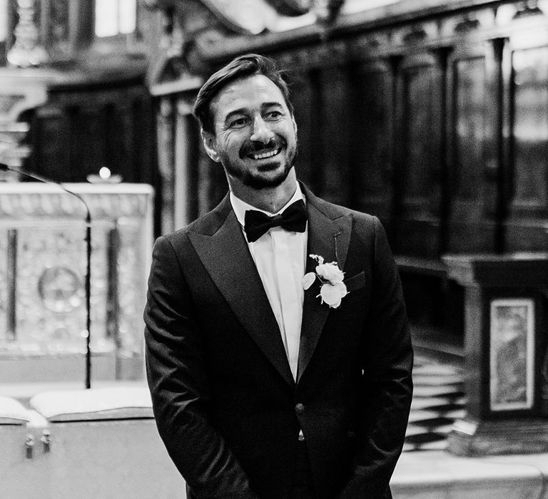 Groom wears black tie and smiles in black & white photo on his wedding day