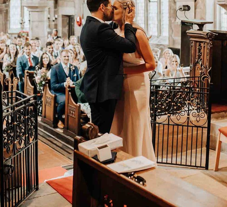 Bride and groom kiss at the altar with brass band wedding entertainment playing