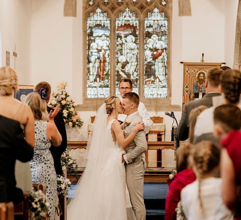 Bride and groom kiss at church wedding ceremony