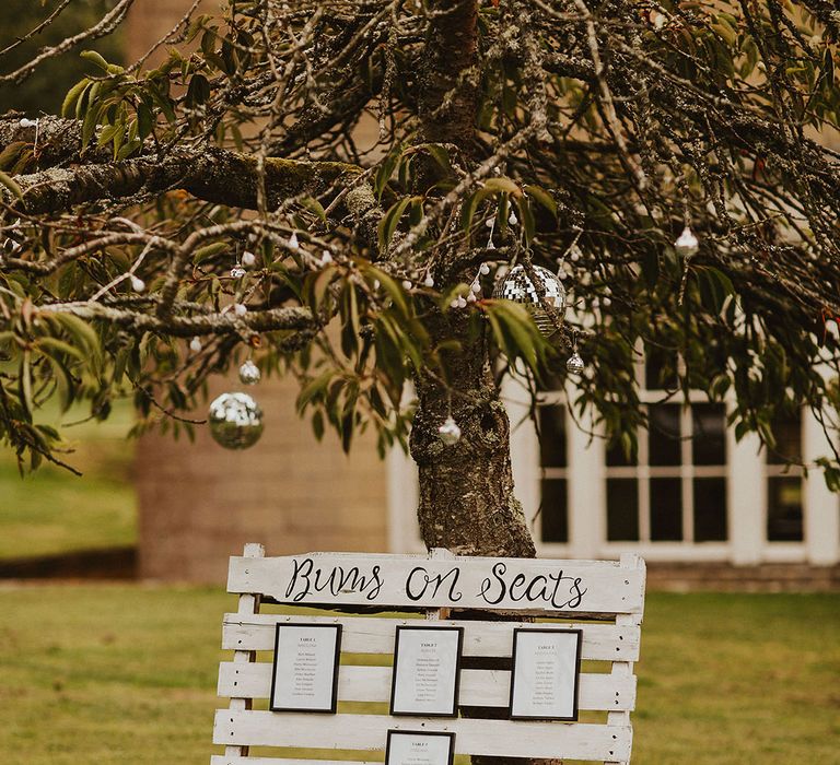 DIY white pallet 'Bums On Seat's' signage for wedding reception table plan