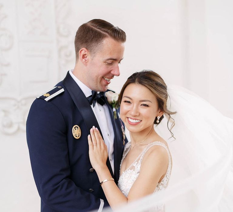 Bride leans in to her groom as her veil blows around her