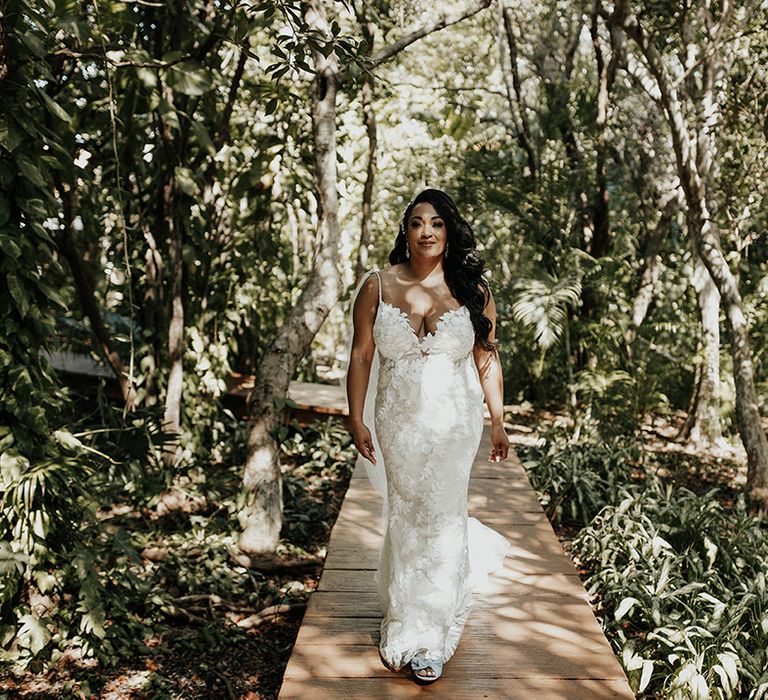 Bride walks in jungle amongst nature in lace floral v-neck wedding dress in Tulum