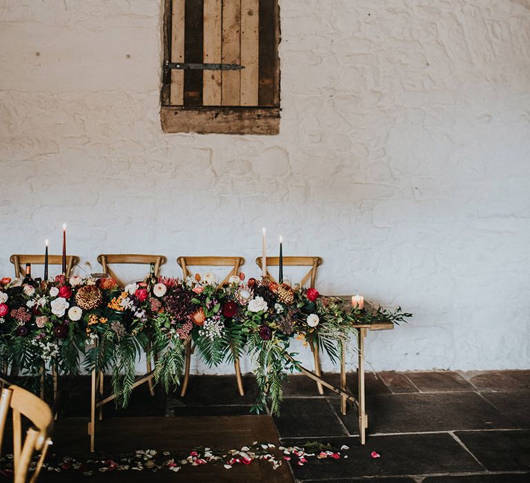 Top table wedding flower arrangement with green foliage, red roses and pink carnations 