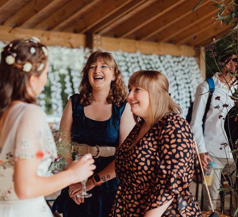 Bride with flowers in her hair socialises with wedding guests