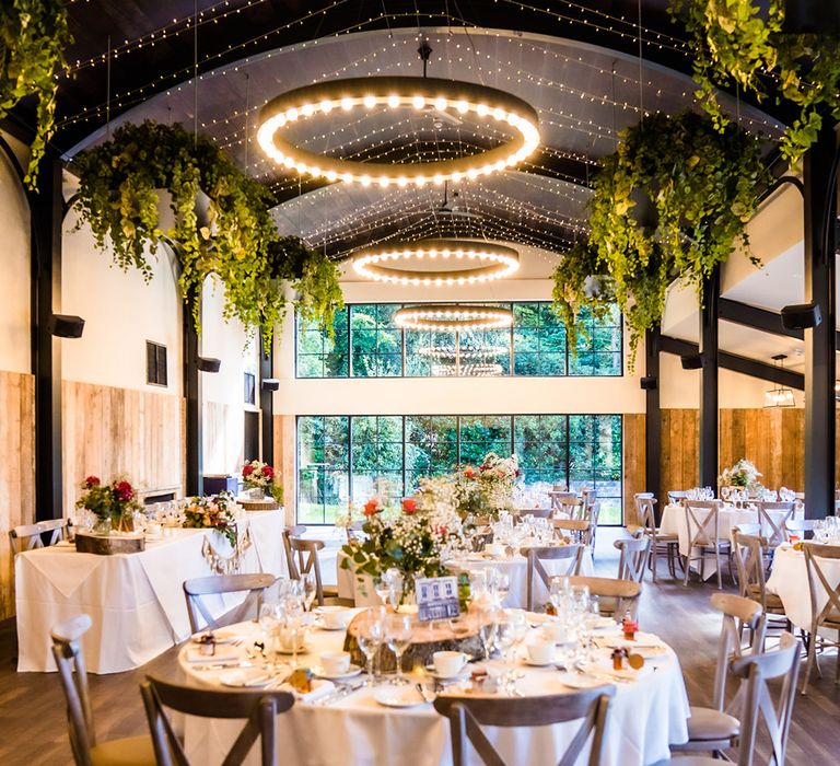 Reception area with grey chairs, tree trunk centrepieces and decorative greenery