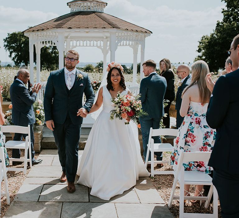 Bride and groom exit their outdoor wedding ceremony at St Tewdrics House in Wales