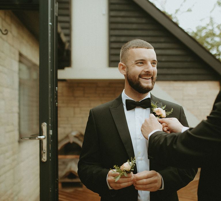 Groom puts on the best man's buttonhole 