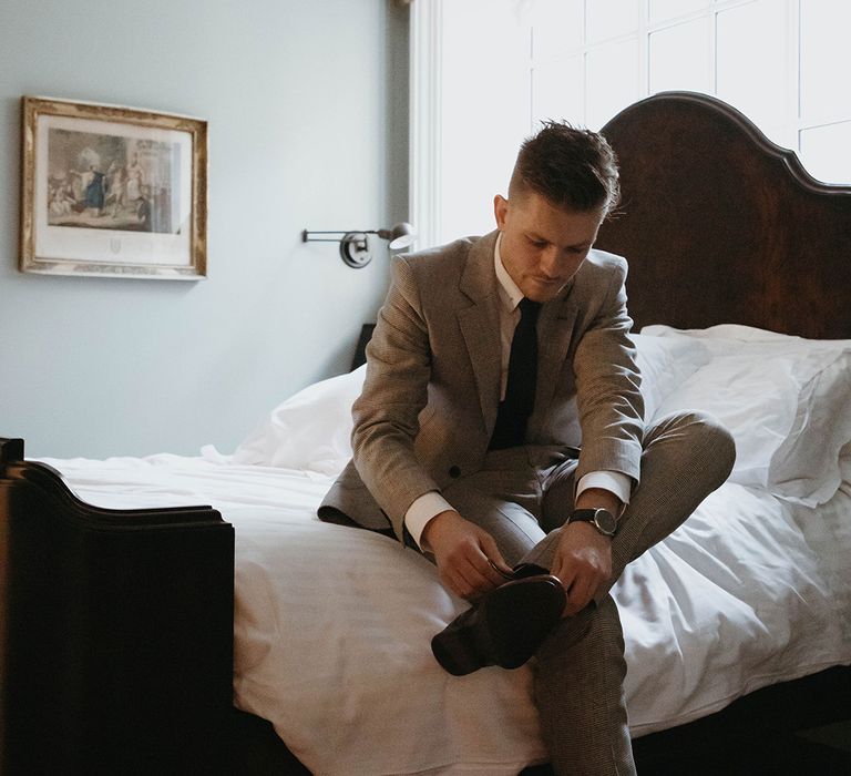 Groom gets ready for his wedding day by putting on his shoes 