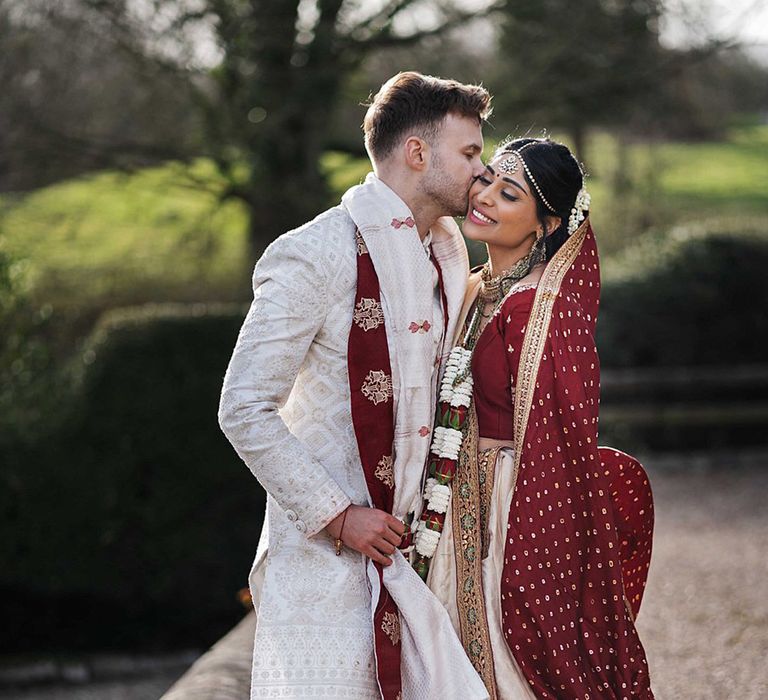 Groom kisses the bride on her cheek after their second wedding ceremony for multicultural wedding