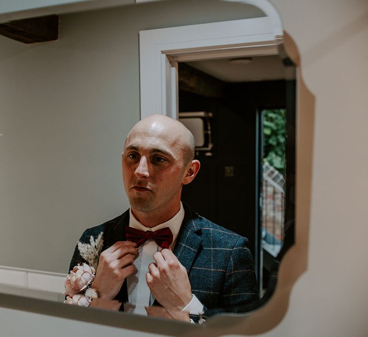 Groom wears red bow tie and tartan blazer complete with white shirt 