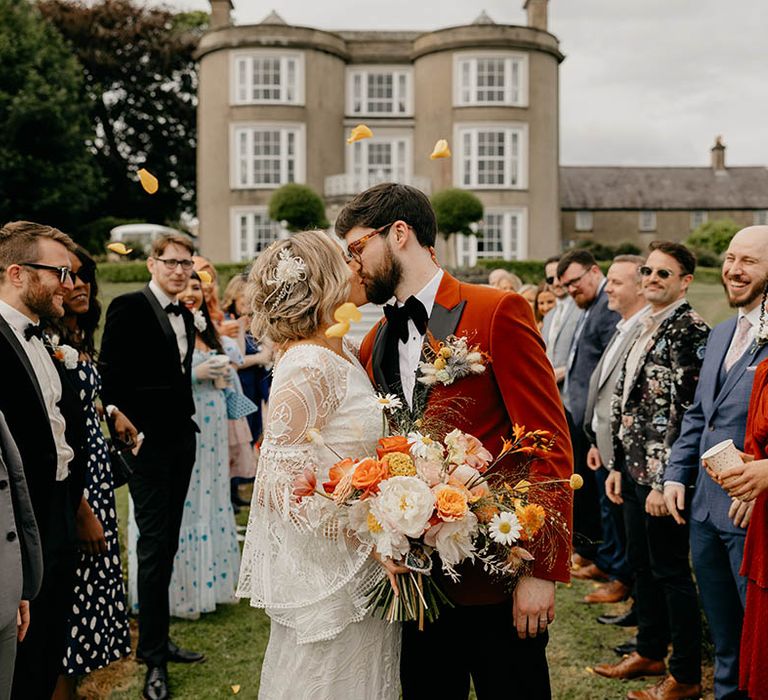 Bride and grooms kiss for their confetti exit after their humanist and handfasting wedding ceremony 